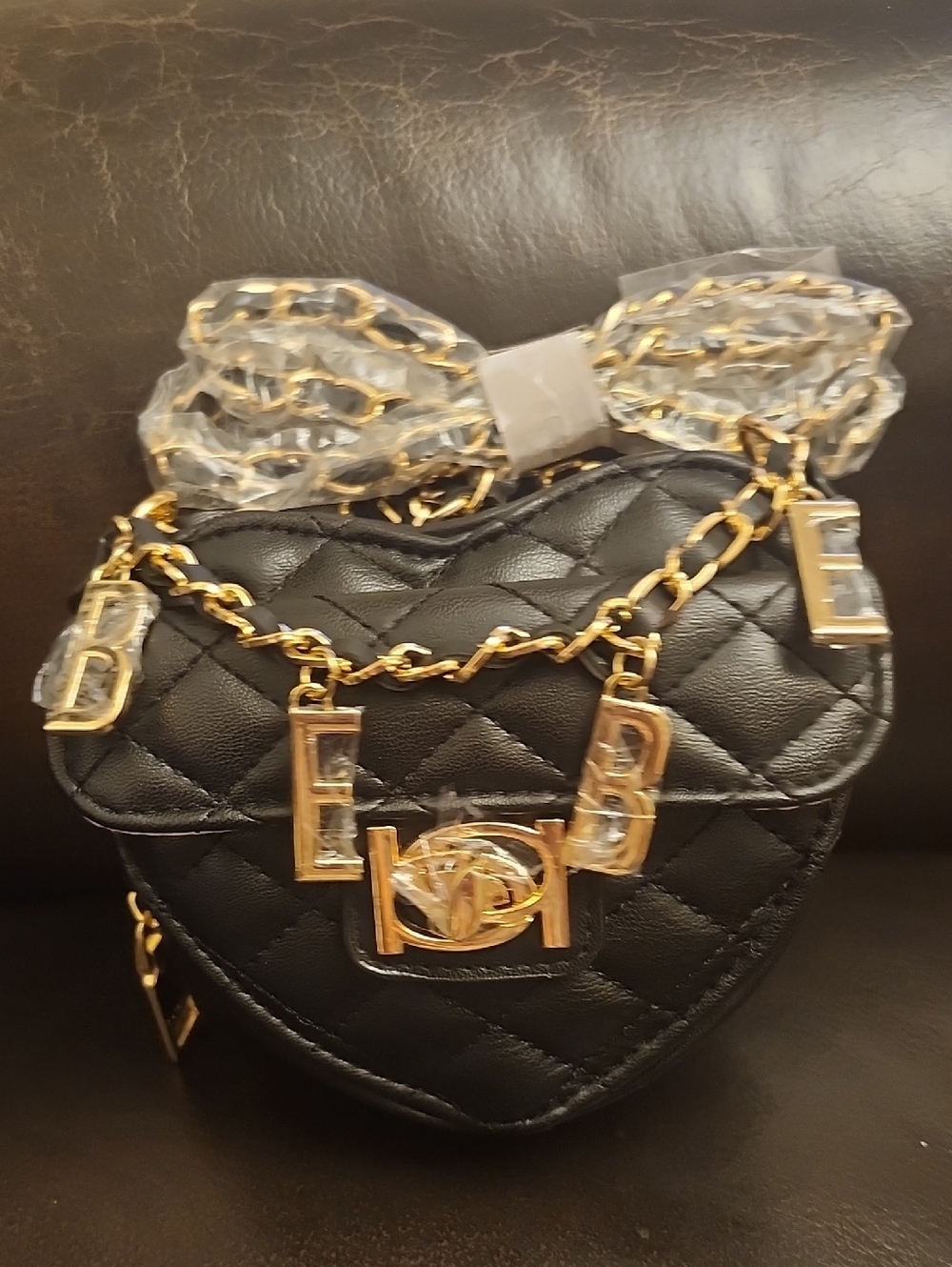 bebe Black Quilted Heart Crossbody with Gold Chain and Letter Charms. Bebe Solan